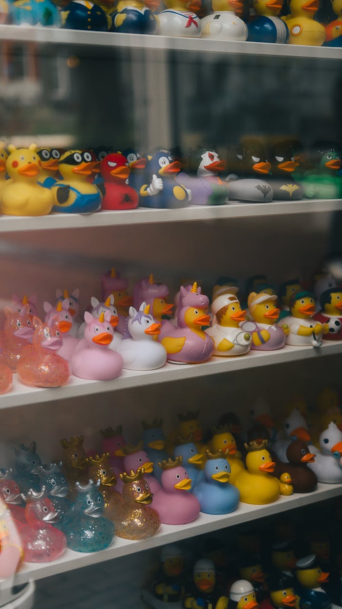 Vibrant collection of decorated rubber ducks on shelves behind glass in a store.