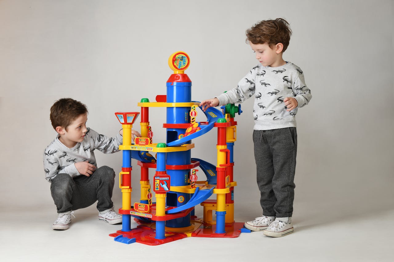Two boys engaging with a vibrant toy tower in a studio setting, showcasing playful childhood moments.